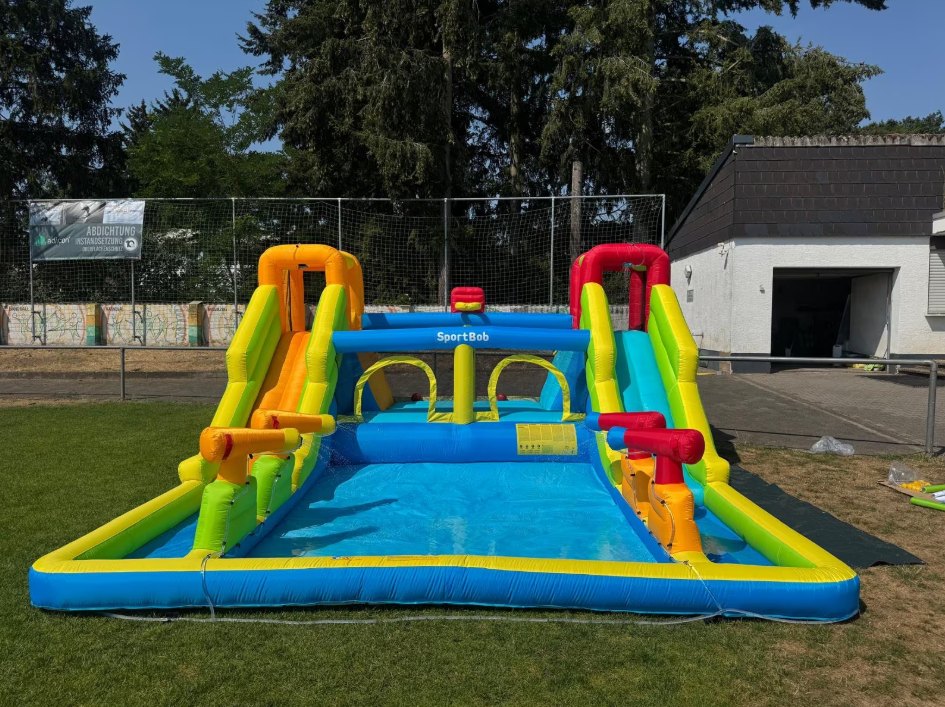 Aufgebaute XXL-Hüpfburg mit zwei Wasserrutschen und Planschbecken im Garten